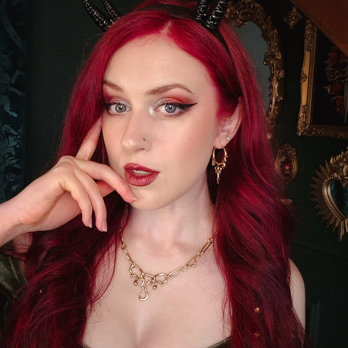 Red-haired model wearing a gold Hellflame Blade hoop earring