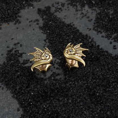 Gold Abyss Conch Ear Studs displayed on black sand, highlighting the curled conch shape, fin-like ridges, and black zircon detail.