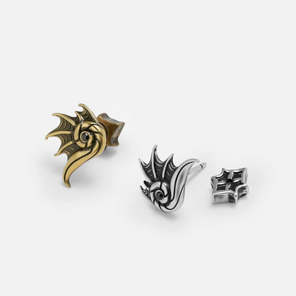 Silver and gold Abyss Conch Ear Studs shown together, featuring curled conch shapes, black zircon centers, and flat back posts.