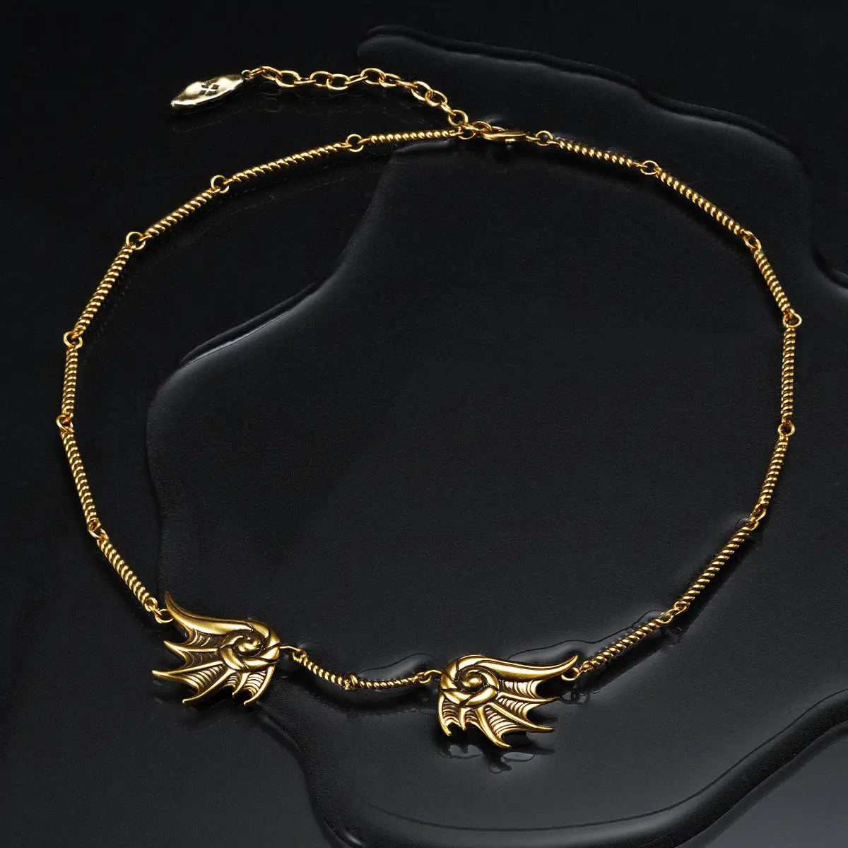 Gold Abyssal Bind Necklace displayed on a dark wet surface, highlighting the shell-like forms and central rope chain detail.