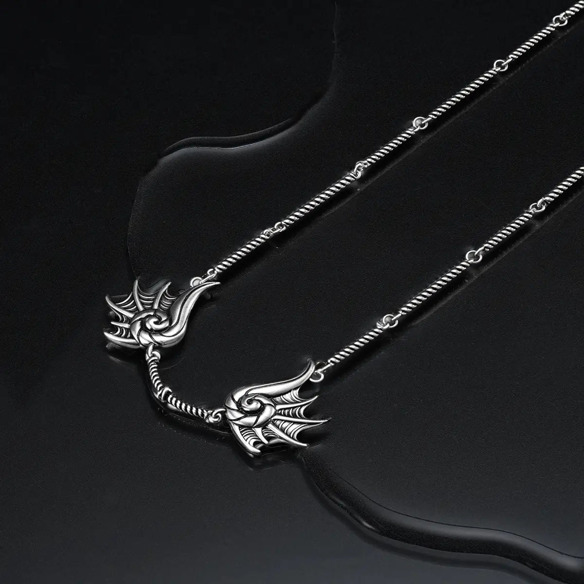 Silver Abyssal Bind Necklace displayed on a dark wet surface, featuring shell-like ridges, a central tether detail, and sea-worn gothic mood.