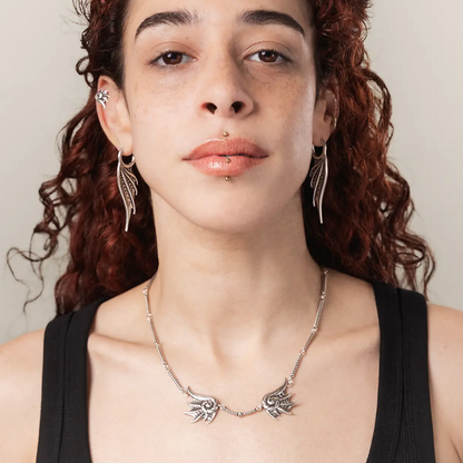 Model wearing the silver Abyssal Bind Necklace, featuring twin conch-like forms, shell ridges, and dark sea-inspired styling.