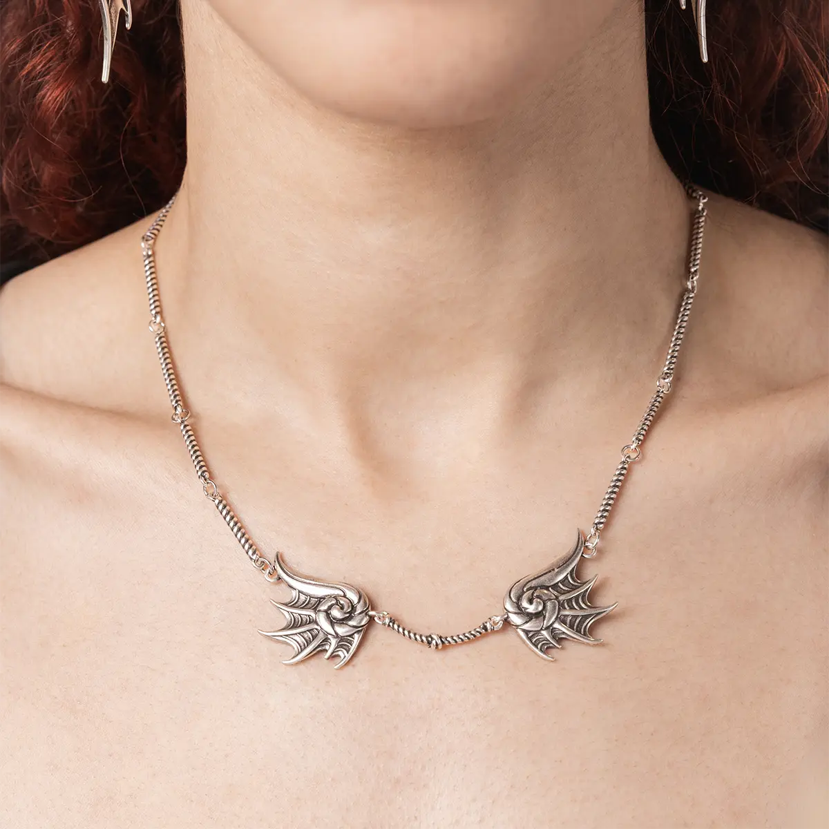 Model wearing the silver Abyssal Bind Necklace, showing the twin shell-like forms and central rope chain detail across the neck.