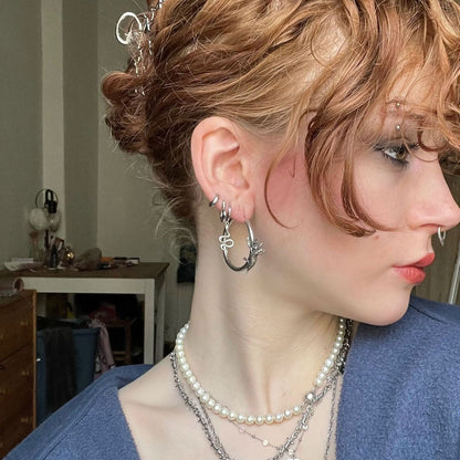 Adaptive Evolution Earrings in 925 sterling silver, worn in side profile with a curly updo, pearl layers, and a mixed silver 