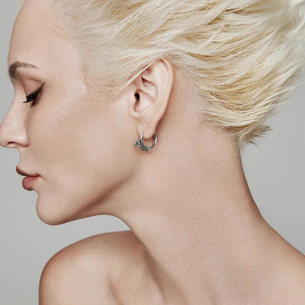 Adaptive Evolution Earrings in 925 sterling silver, worn in a closer platinum-blonde side profile with the dragon hoop center