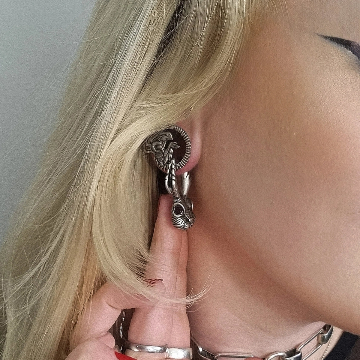 Close-up of an alien invasion tunnel worn in the ear, showing ridged edge and creature design
