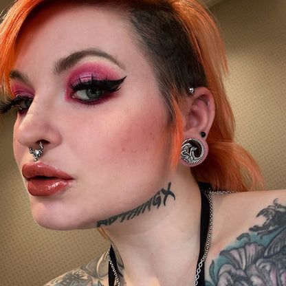 Model wearing a silver Alien Invasion ear tunnel with biomechanical creature motif