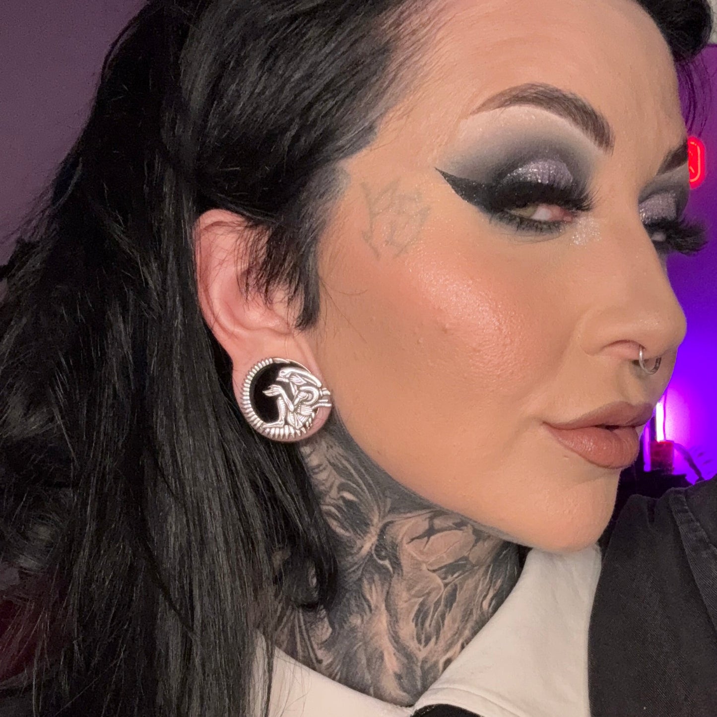 Silver-tone alien tunnel earring worn in a stretched lobe, shown against dark hair