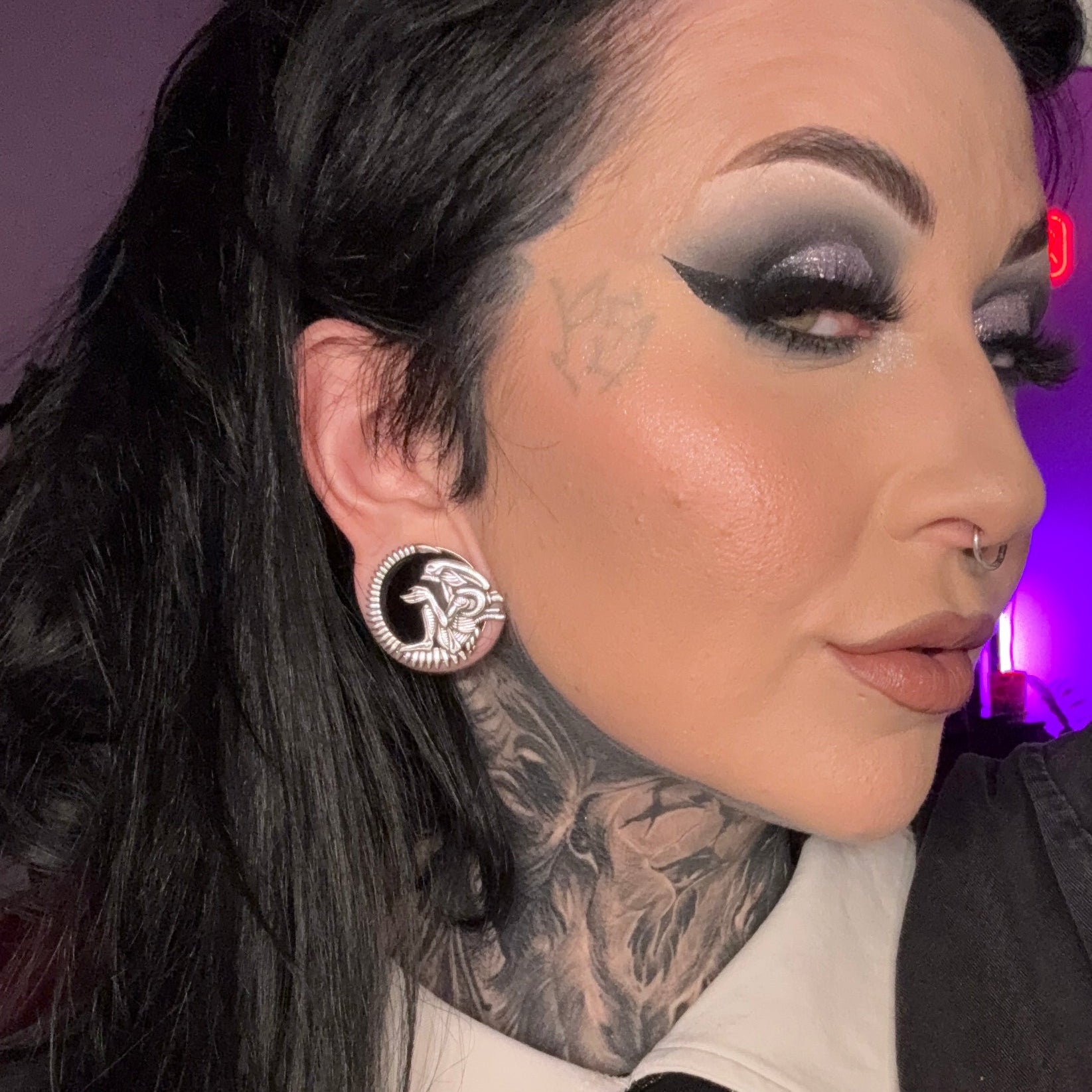 Silver-tone alien tunnel earring worn in a stretched lobe, shown against dark hair