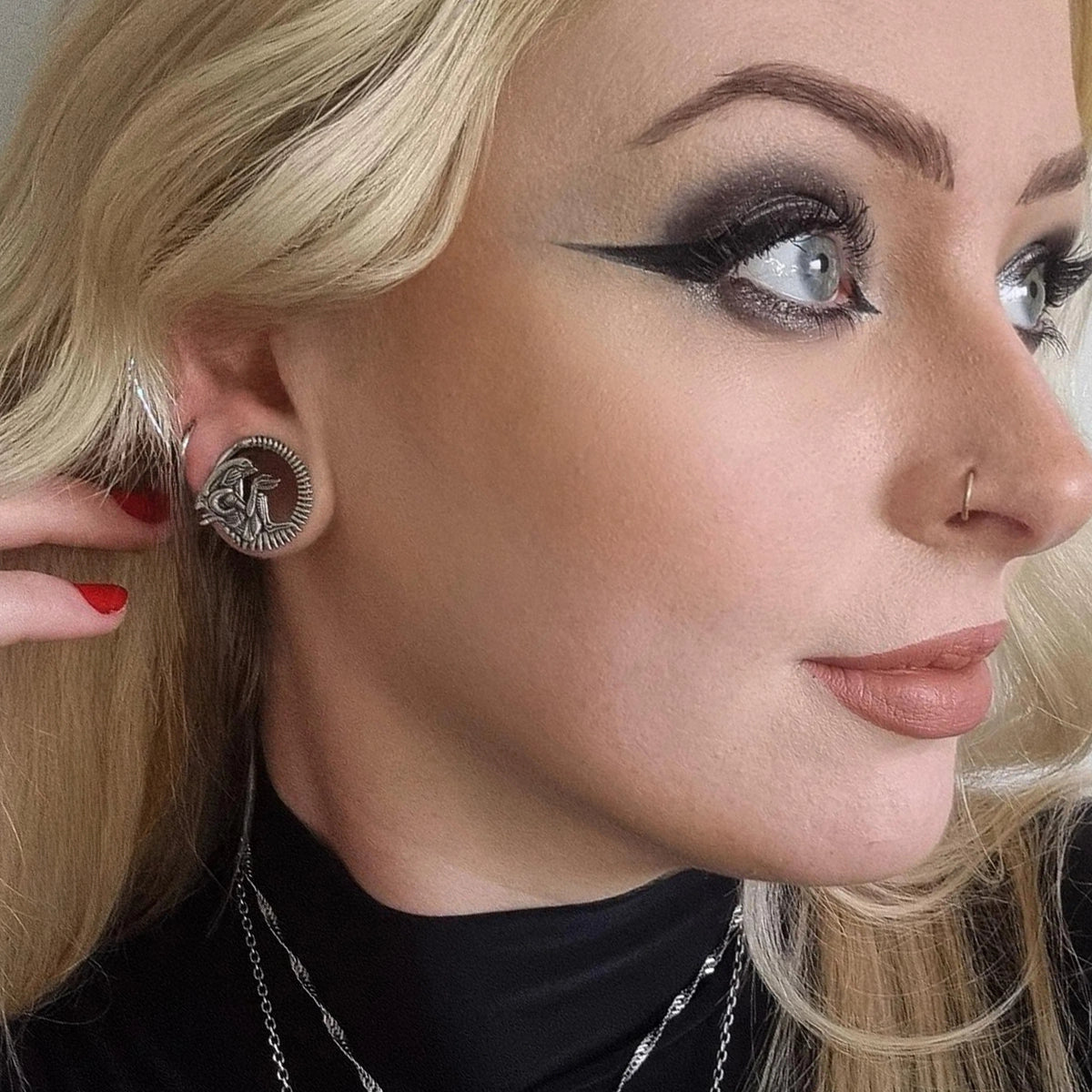 Model wearing a silver-tone alien tunnel earring in a stretched ear lobe, close side profile
