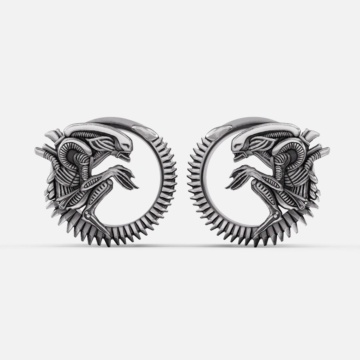 Pair of silver-tone alien invasion tunnels with ridged spine detail and coiled creature motif, front view