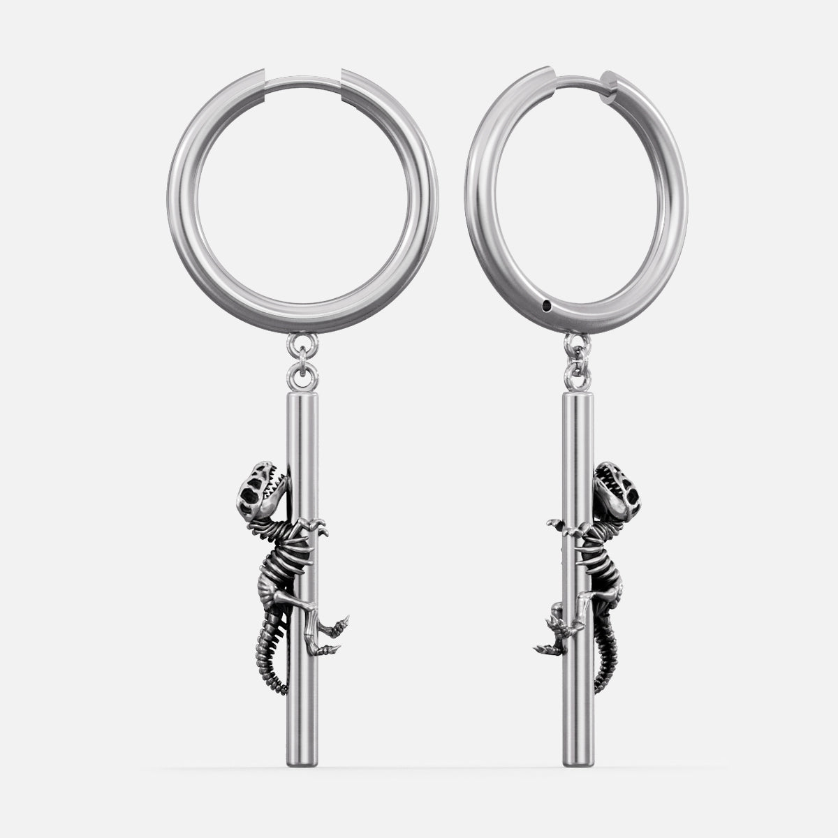Silver-tone hoop earrings with a dangling dinosaur skeleton charm climbing a bar, shown as a pair