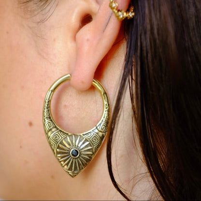 Close-up of a model wearing an antique gold-tone hoop earring with sunburst medallion detail