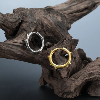 Ancient Thorn Hoops in gold and silver displayed on driftwood with dark woodland styling
