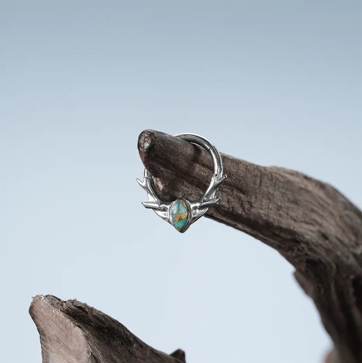Silver Antler Mark Clicker with turquoise stone photographed on driftwood