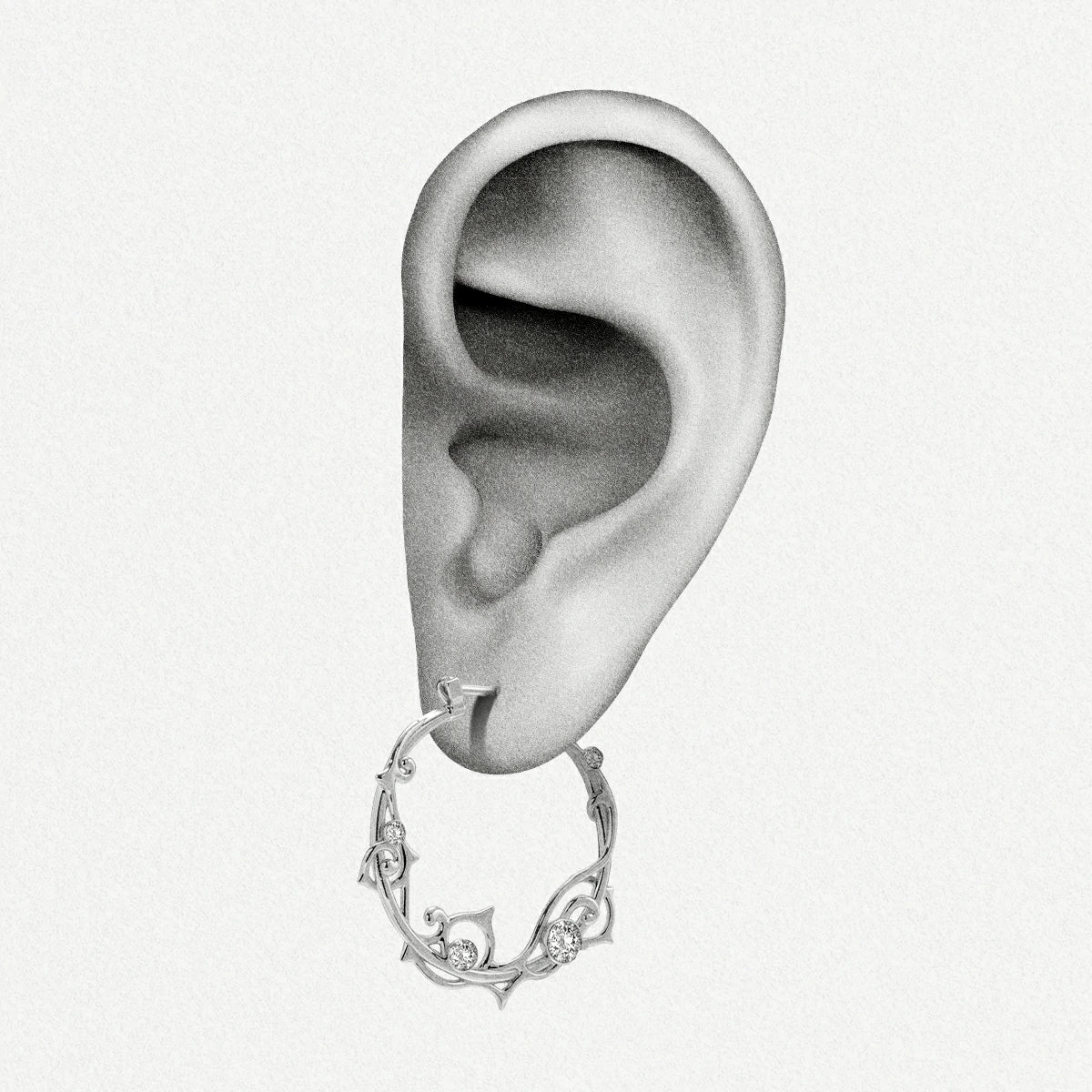 Silver-tone vine hoop earring with clear stones shown hanging from an illustrated ear