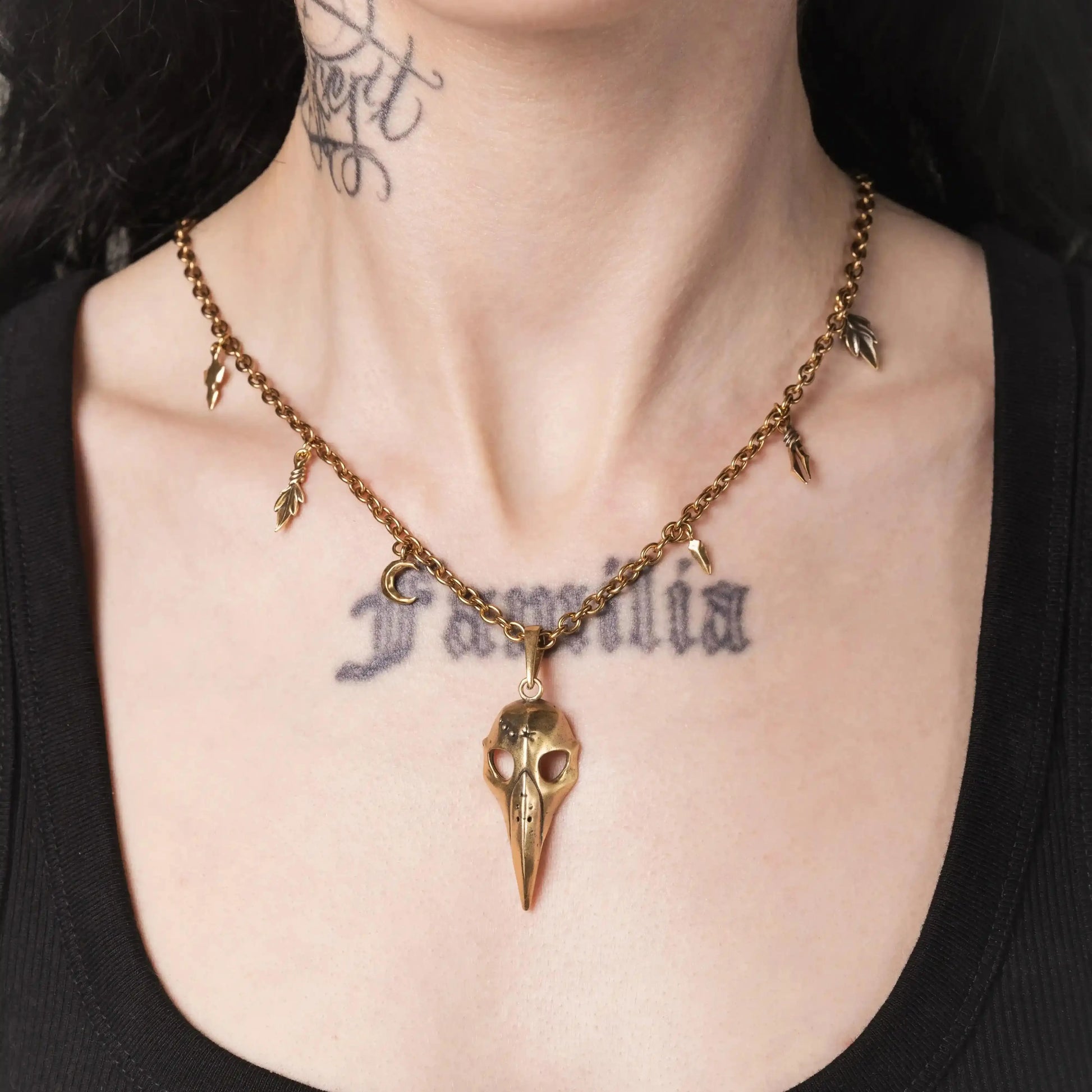 Model wearing the gold Augur Skull Necklace with long bird skull pendant and leaf charms