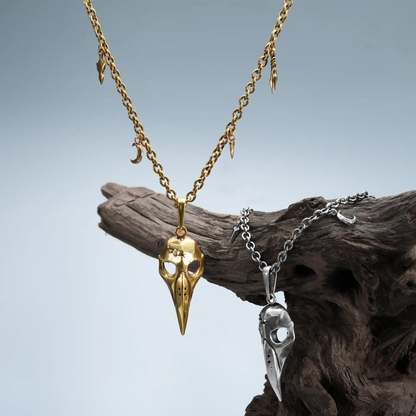 Augur Skull Necklace in gold and silver displayed on driftwood with dark woodland styling