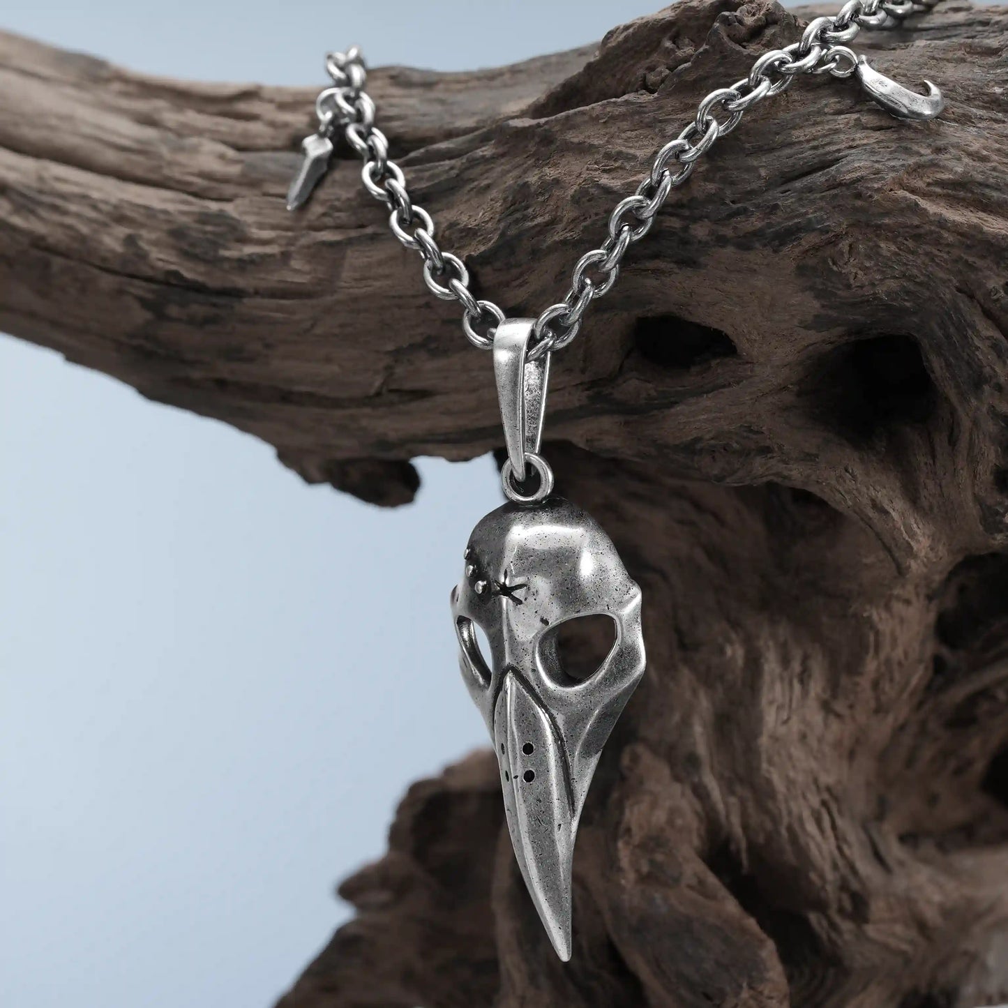 Silver Augur Skull Necklace hanging on weathered wood with bird skull pendant detail
