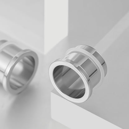 Polished silver Aurora ear tunnel shown at an angle on a white geometric display