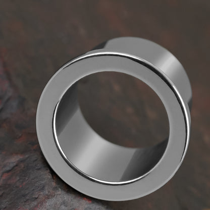 Macro view of a polished silver Aurora ear tunnel showing its rounded flared rim and inner channel