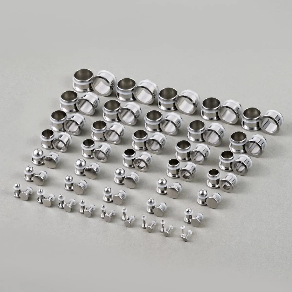 Full set of steel ear stretching plugs and tunnels arranged in graduated sizes on a flat surface