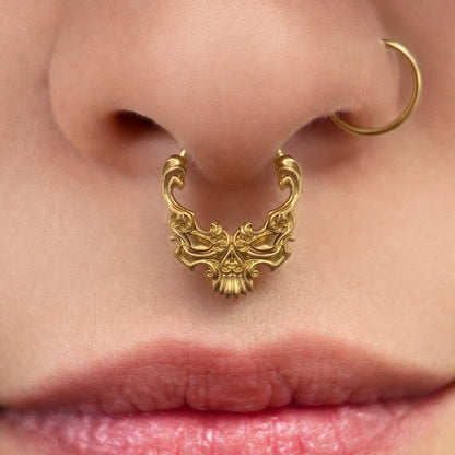 Gold-tone Baroque Skull Clicker worn as a septum ring, showing its detailed skull-inspired silhouette.