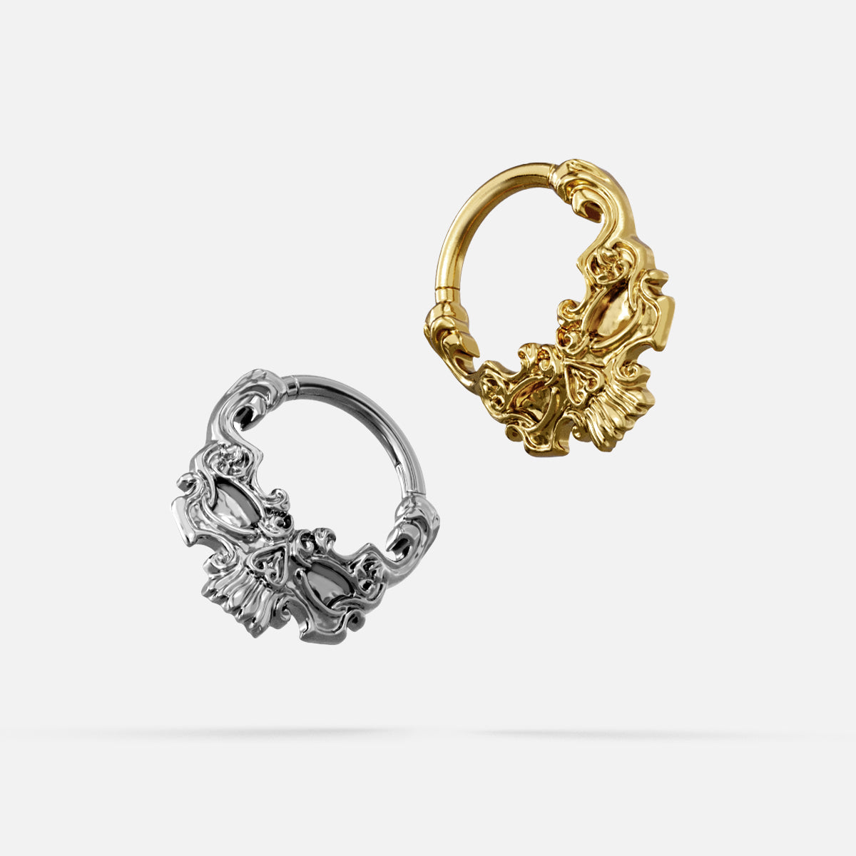 Silver- and gold-tone Baroque Skull Clickers displayed together from angled views on a light gray background.