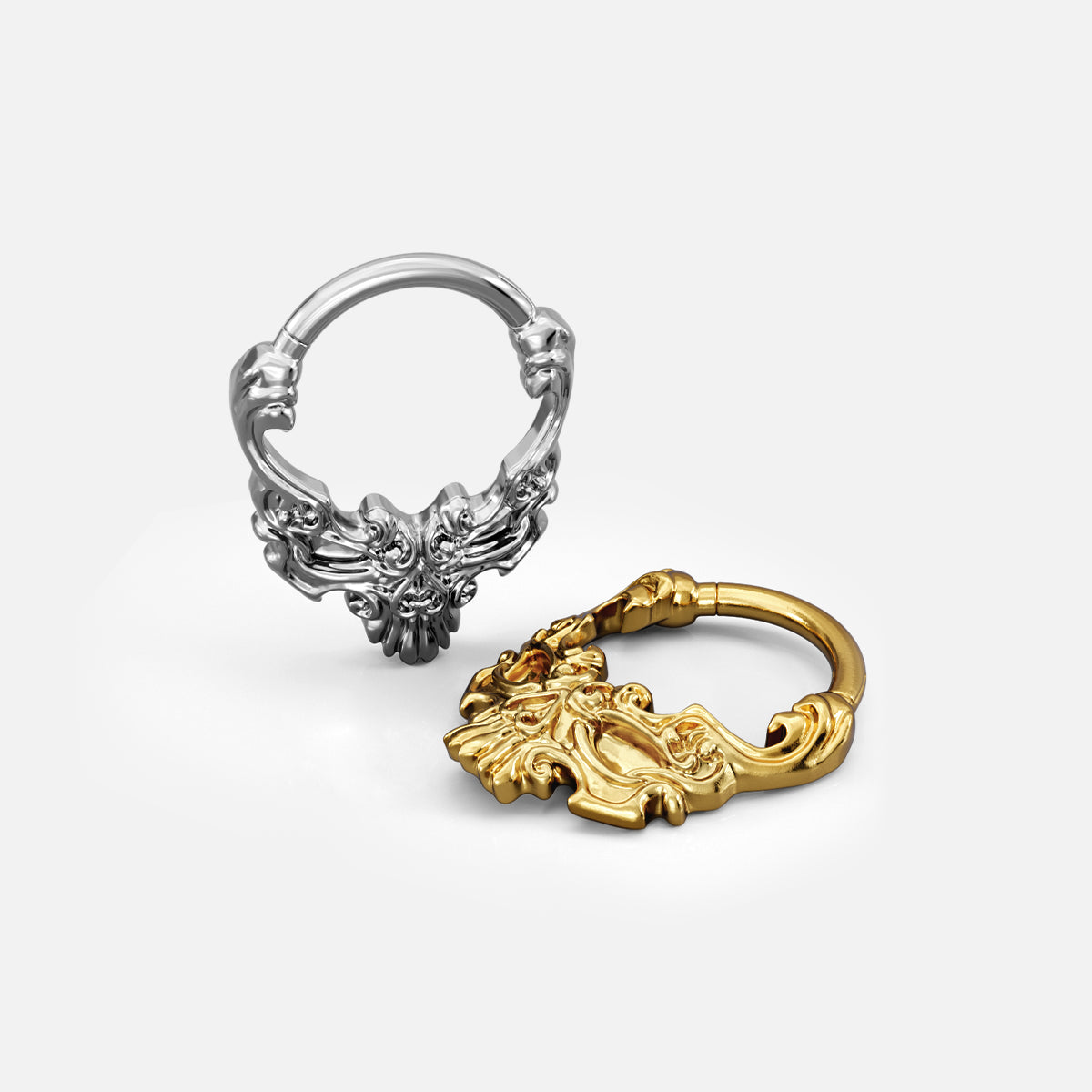 Silver- and gold-tone Baroque Skull Clickers shown from multiple angles to display the ring profile and raised skull motif.