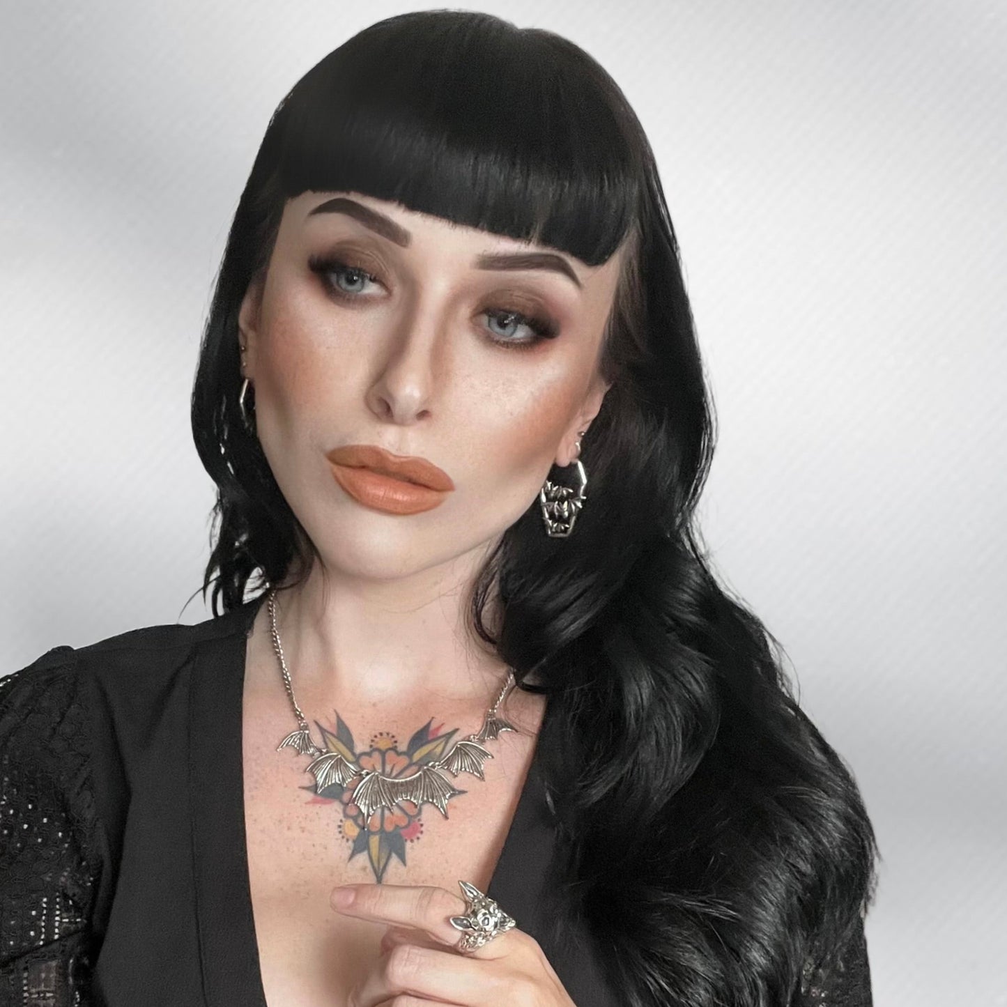 Model wearing a gold Bat Tomb coffin hoop earring