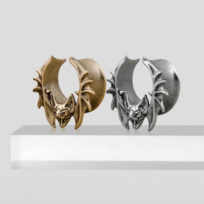 Gold and silver Bat Whisper tunnels displayed upright on a white pedestal