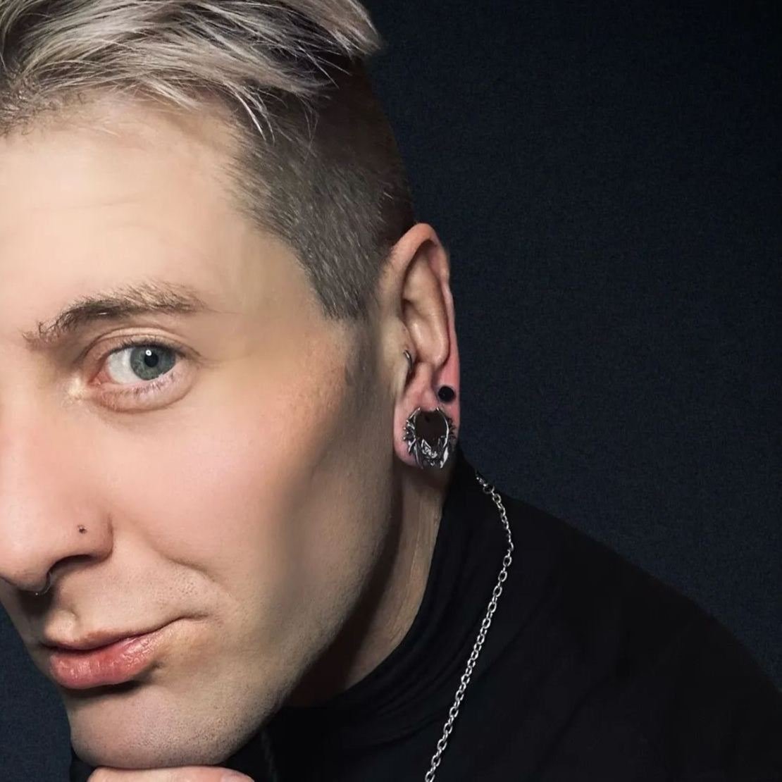 Model with short hair wearing a silver-tone bat tunnel earring and a thin chain necklace