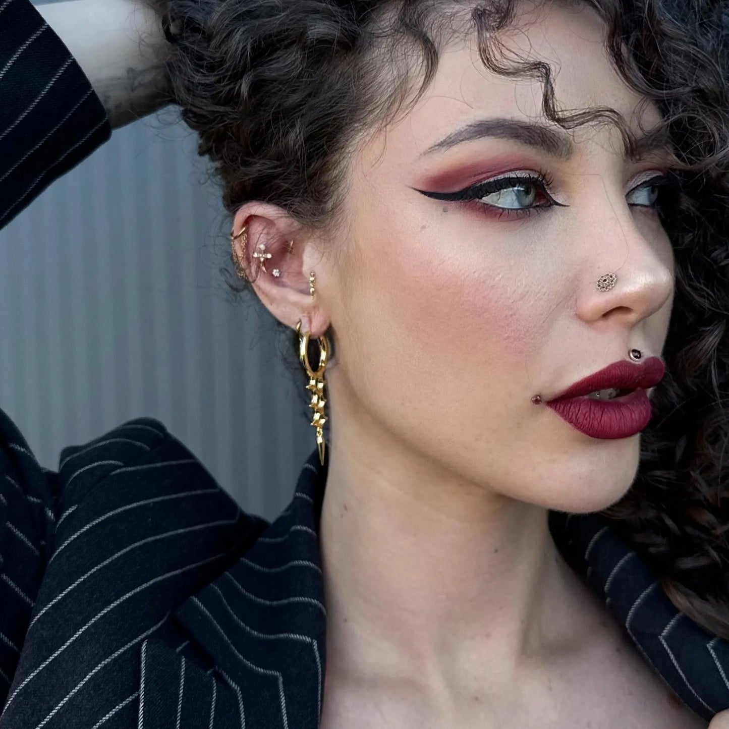 Model wearing gold Biomech Spine Earrings with spine-inspired structure and spike drop design