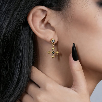 Black Testament Earrings in antiqued 18K gold worn on the ear in a close profile crop with a hand at the neck.