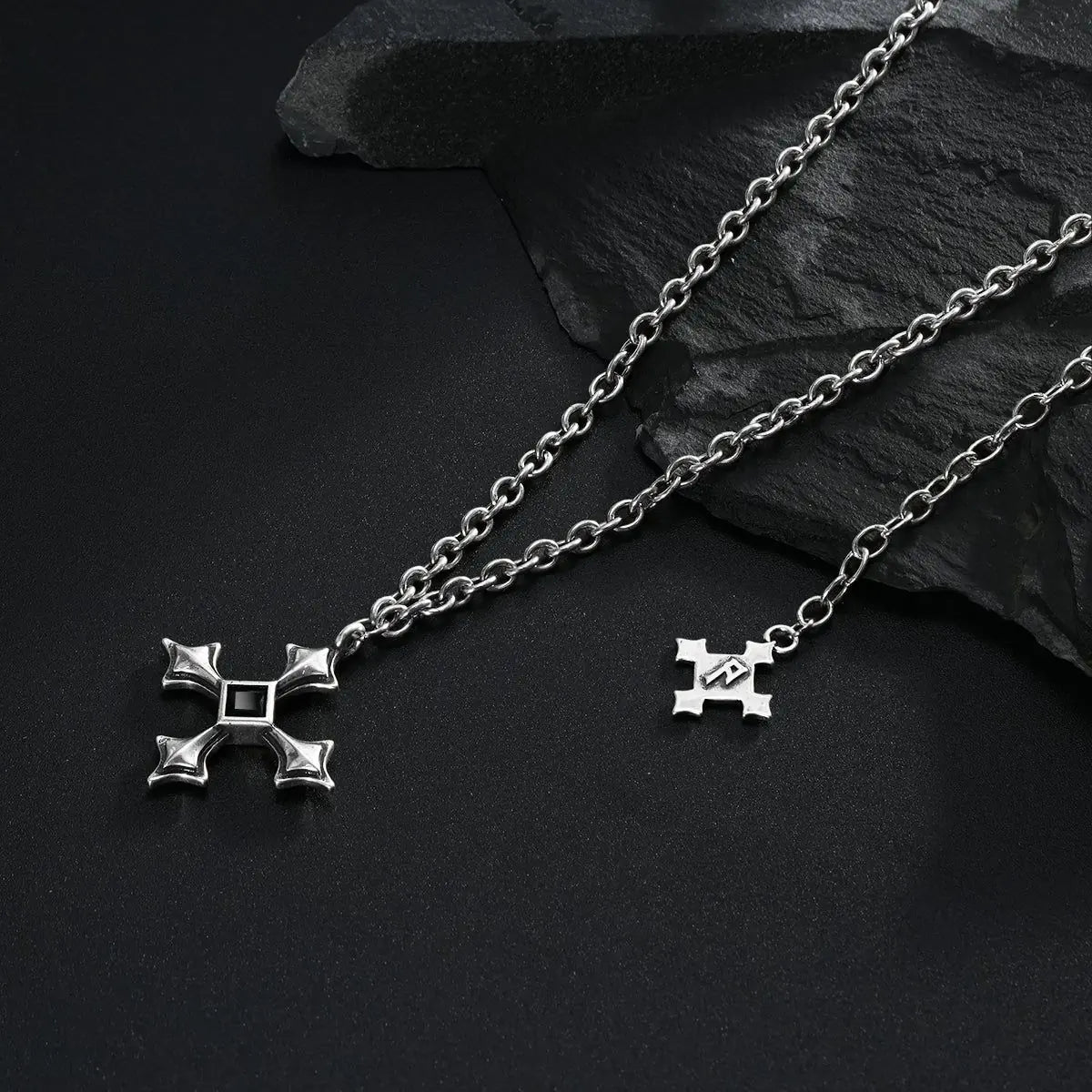 Silver Black Testament Necklace laid across black textured fabric with the gothic cross pendant in view.