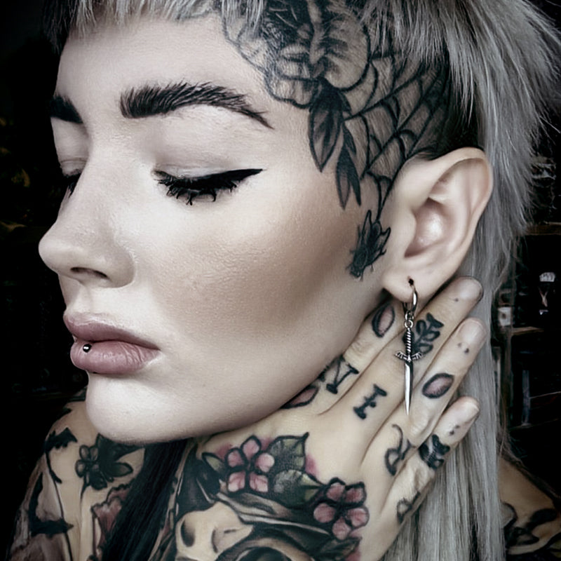 Model wearing a silver Blade Wing drop earring beside multiple ear piercings