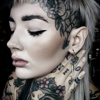 Model wearing a silver Blade Wing drop earring beside multiple ear piercings