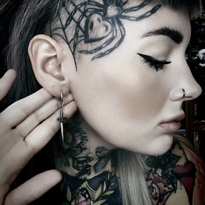 Side view of model wearing a silver Blade Wing earring with a long pointed drop