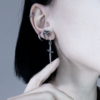 Side view of model wearing a silver-tone sword earring with winged top, styled with additional ear hoops