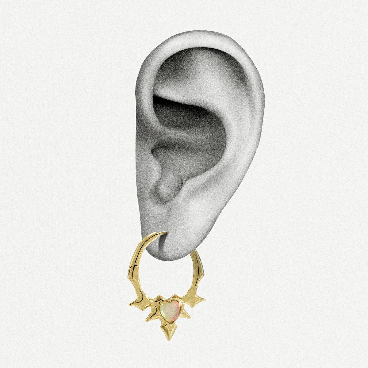 Gold-tone spiked hoop earring with an opal heart center worn on an ear illustration