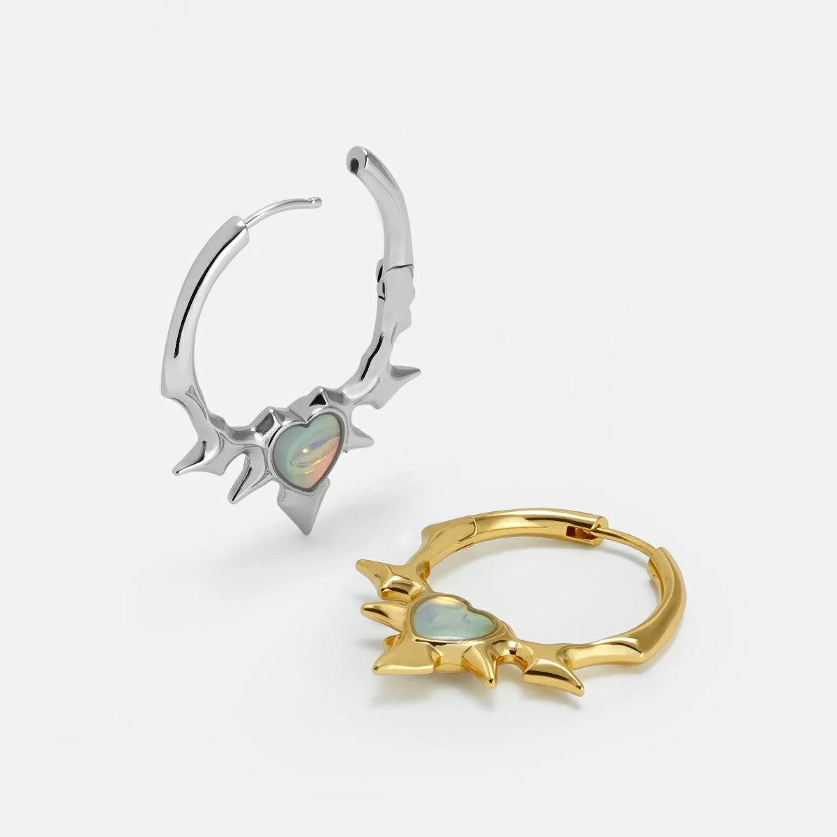 Silver-tone and gold-tone spiked hoop earrings with opal heart centers shown side by side