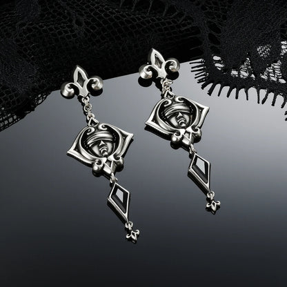 Antiqued silver-tone Blind Oracle Drop Earrings displayed from angled views against black lace on a reflective surface.