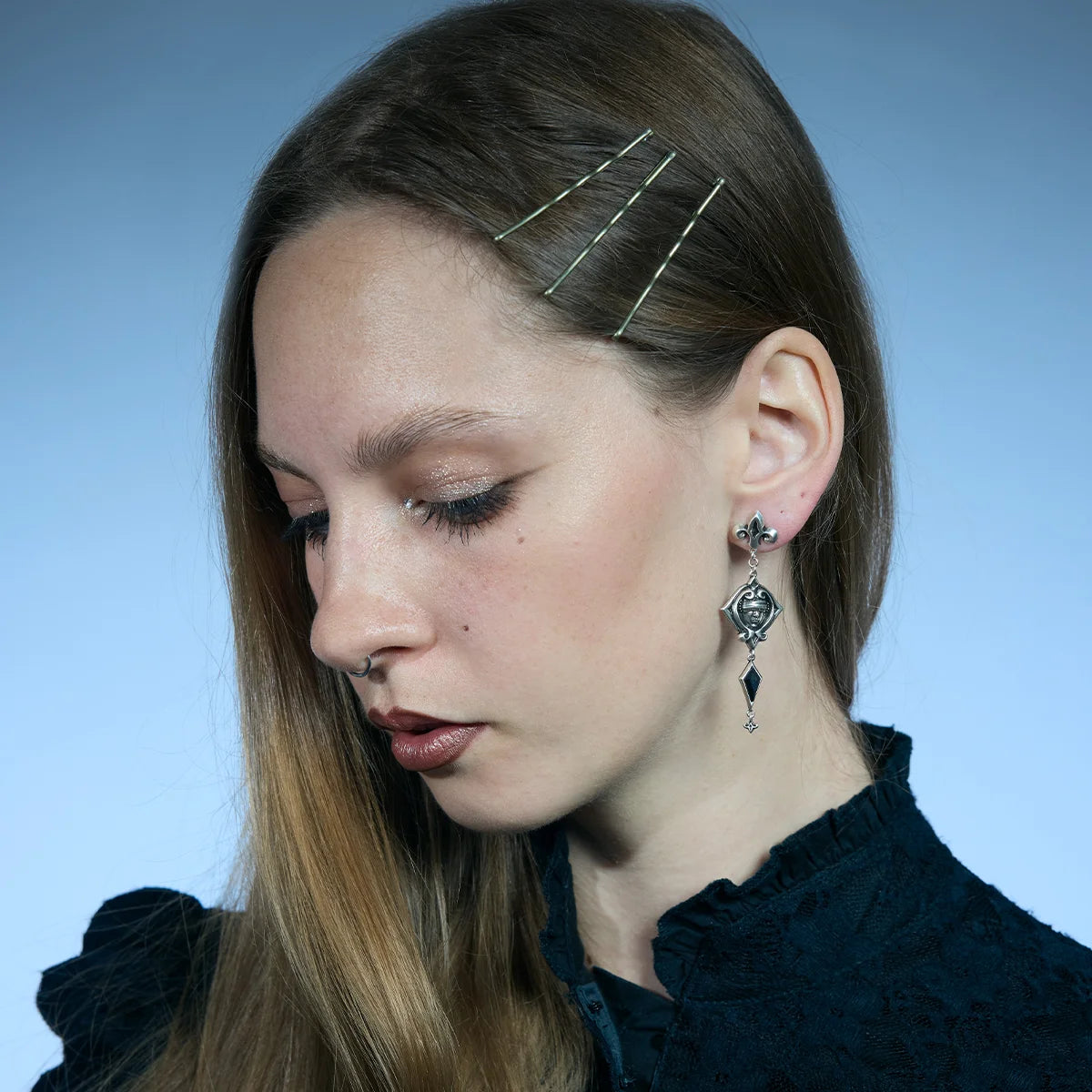 Antiqued silver-tone Blind Oracle Drop Earrings worn in a downward-looking portrait, highlighting their elongated movement.