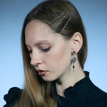 Antiqued silver-tone Blind Oracle Drop Earrings worn in a downward-looking portrait, highlighting their elongated movement.