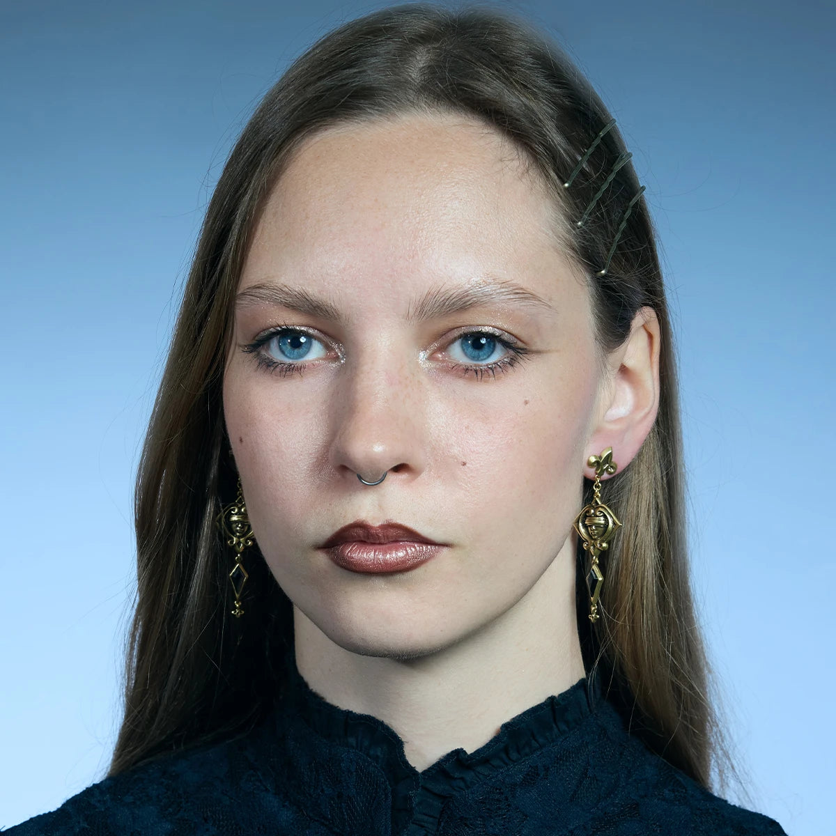 Front portrait showing a pair of antiqued silver-tone Blind Oracle Drop Earrings hanging along the jawline.