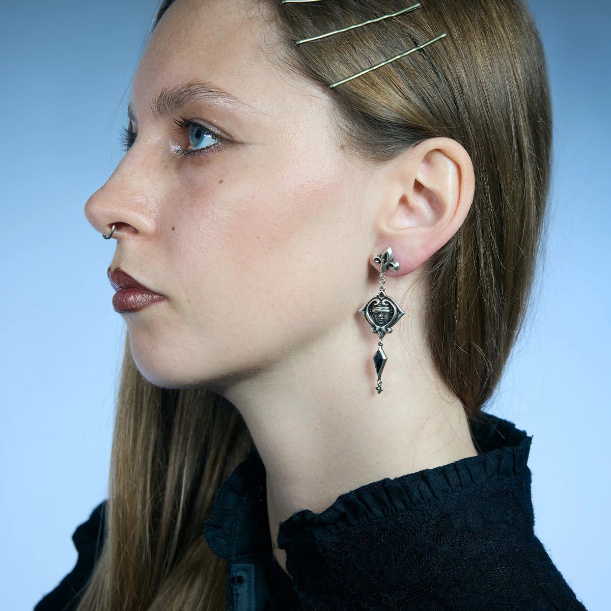 Side portrait showing an antiqued silver-tone Blind Oracle Drop Earring with three linked sections falling below the lobe.
