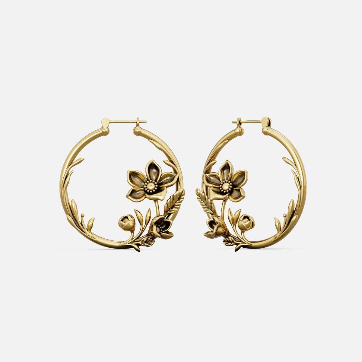 Pair of gold-tone hoop earrings featuring a vine and flower design, shown against a plain background