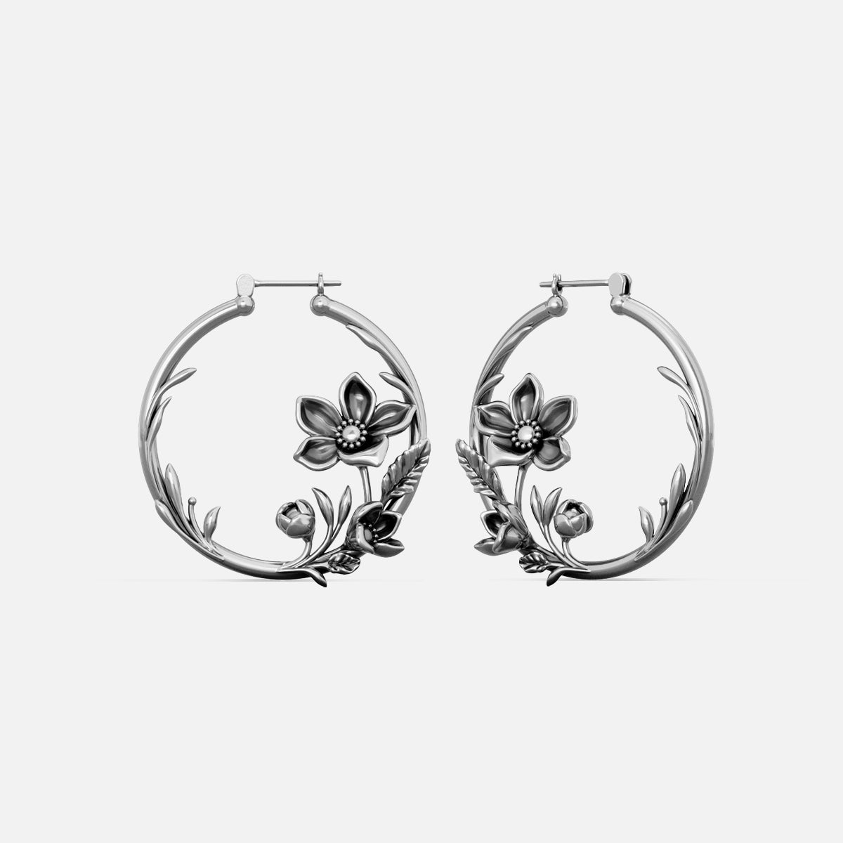 Pair of silver-tone hoop earrings with a vine and blossom motif, shown against a plain background