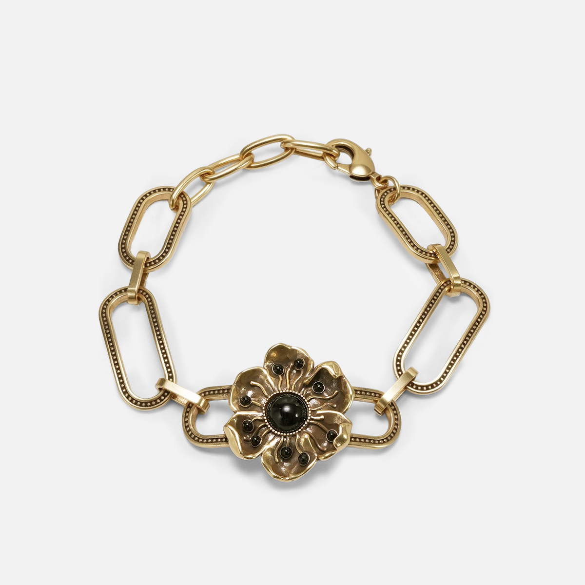 Gold-tone bracelet featuring paperclip chain links and a flower charm with a dark green center stone