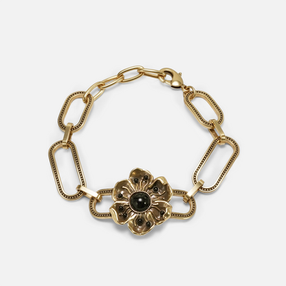 Gold-tone bracelet featuring paperclip chain links and a flower charm with a dark green center stone
